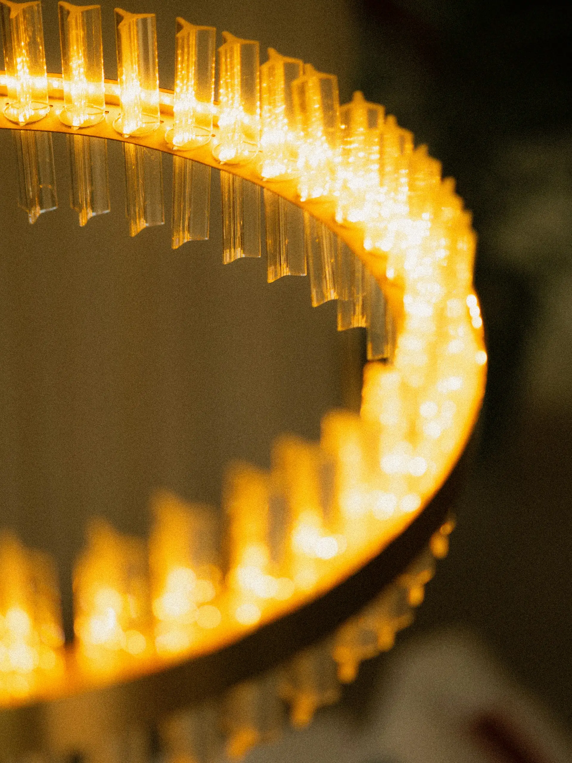 A crystal ring chandelier glowing warm against a dark showroom